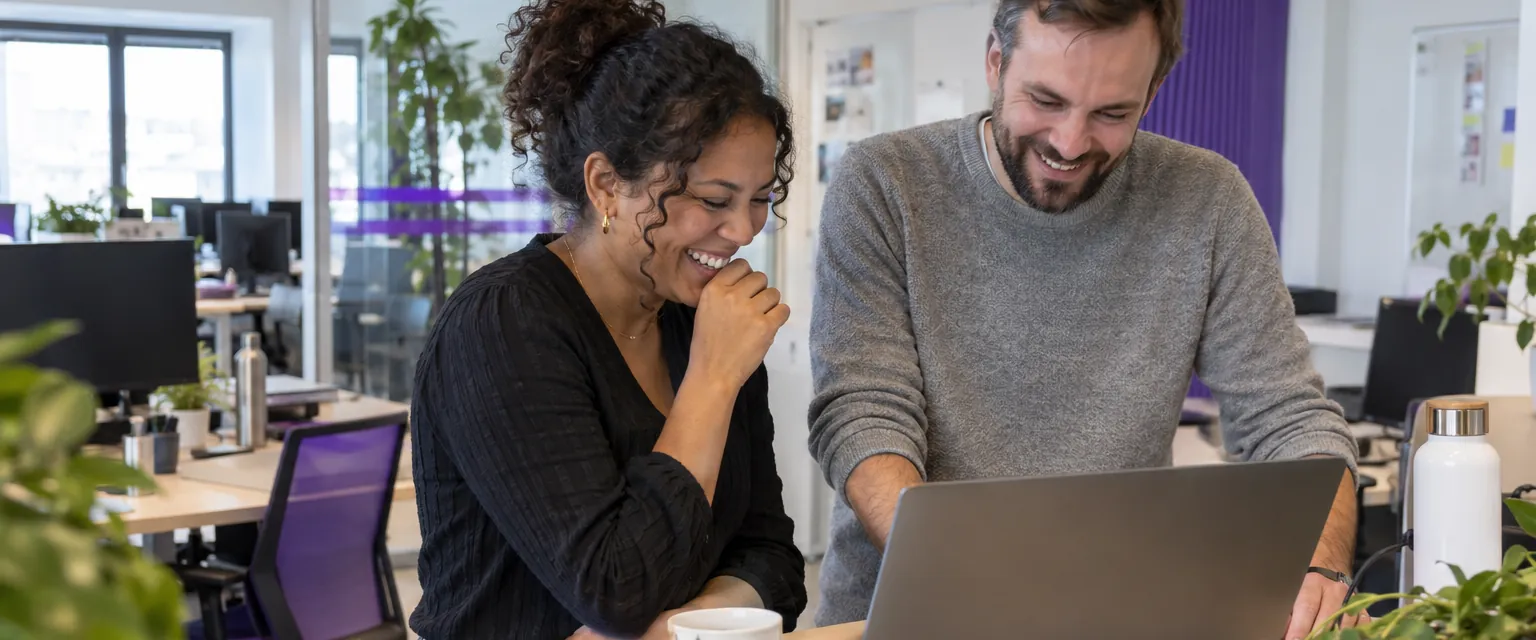 Deux collègues rient devant un ordinateur portable